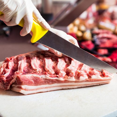 bigstock-Butcher-woman-cutting-piece-of-243777553